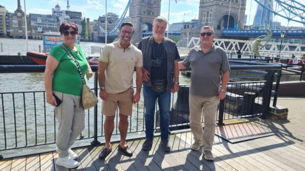 Group of tourists posing for a photo during london bus tours experience at iconic Tower Bridge in London, showcasing sightseeing with London Sightseeing Taxi Tours