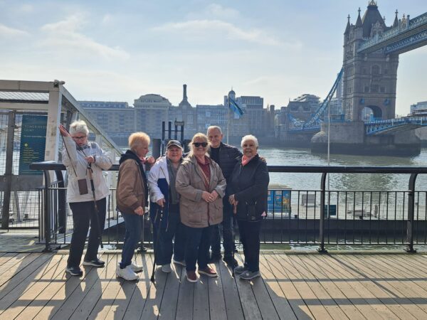 Tourists on London England tours packages posing in front of iconic Tower Bridge during a memorable sightseeing taxi tour