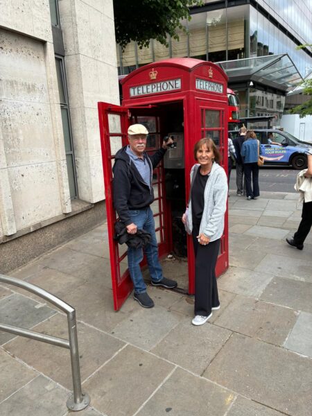 Visitors enjoying trips in London with London Sightseeing Taxi Tours posing at the classic red phone booth