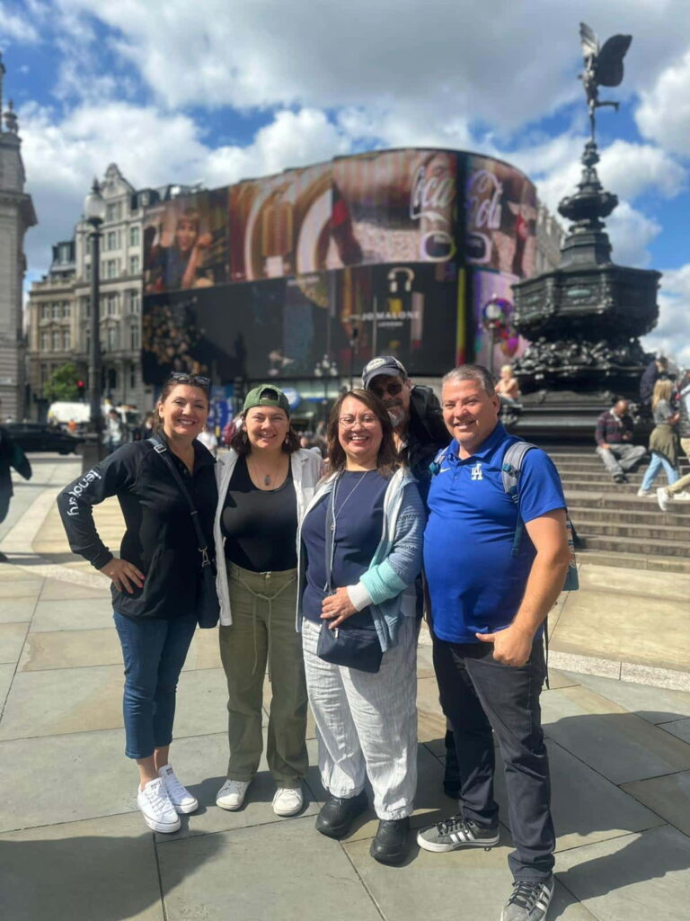 Happy group of tourists posing in front of London Eye before embarking on Cotswolds day tour from London, experiencing scenic countryside and charming villages