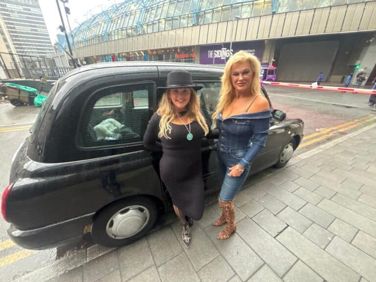 Tourists experiencing UK group tours in London with a black taxi cab